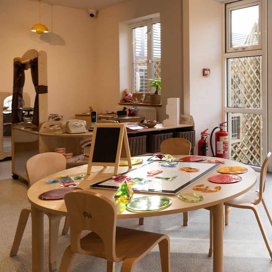 Colorful glass art and craft supplies on a round children's table at Monkey Puzzle Day Nursery & Preschool Lightwater.