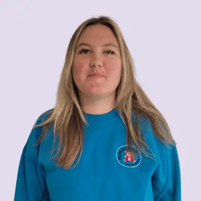Bright young staff member at Monkey Puzzle Day Nursery Lightwater in a blue uniform, part of a caring team dedicated to early childhood education and preschool development.